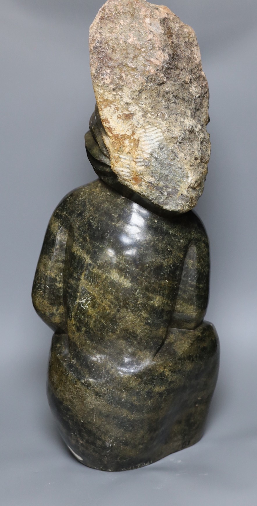 A Zimbabwean carved and polished stone figure with crossed arms and roughly hewn headdress, 70cms.